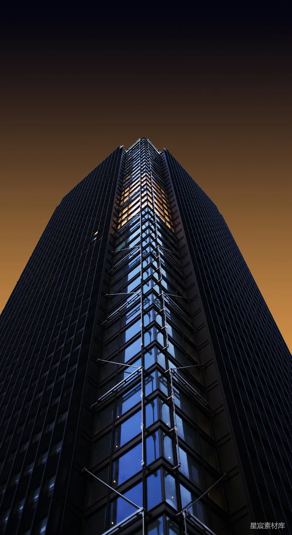 这张图片展示了一座高耸入云的摩天大楼，夕阳的余晖洒在其玻璃幕墙之上，反射出温暖的光芒。大楼的结构线条清晰，现代感十足，给人一种宏伟而庄重的感觉。这幅图像非常适合用于城市风光、建筑设计或现代都市主题的背景或封面设计。