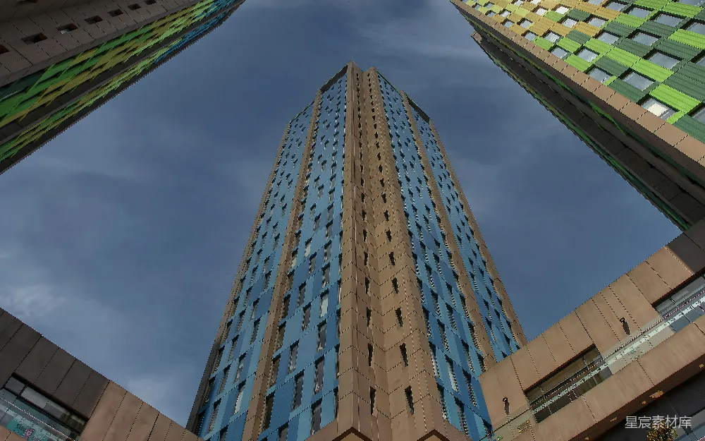这张图片展示了从低角度拍摄的现代城市高楼，天空湛蓝，建筑物的外墙以蓝色和棕色为主，窗户排列整齐，整体给人一种高耸入云、气势恢宏的感觉。适合用于城市建筑、现代都市、景观设计等场景。