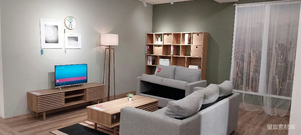 这张图片展示了一个现代简约风格的客厅，采用灰色沙发和木质家具搭配，营造出温馨舒适的氛围。墙上挂着艺术画作，搭配圆形挂钟，增添了装饰感。落地灯和电视柜的设计简洁实用，整体布局合理，适合现代都市生活。