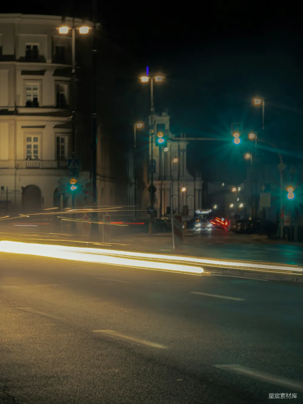 这张图片展示了一个城市的夜景，灯光在夜晚的道路上形成了一道道光轨。街道两旁是现代化的建筑，远处的路灯和信号灯发出柔和的光芒，给人一种宁静而充满活力的感觉。图片的长曝光技术使得车灯和街道灯光形成了流动的光带，增加了画面的视觉冲击力。适合用于城