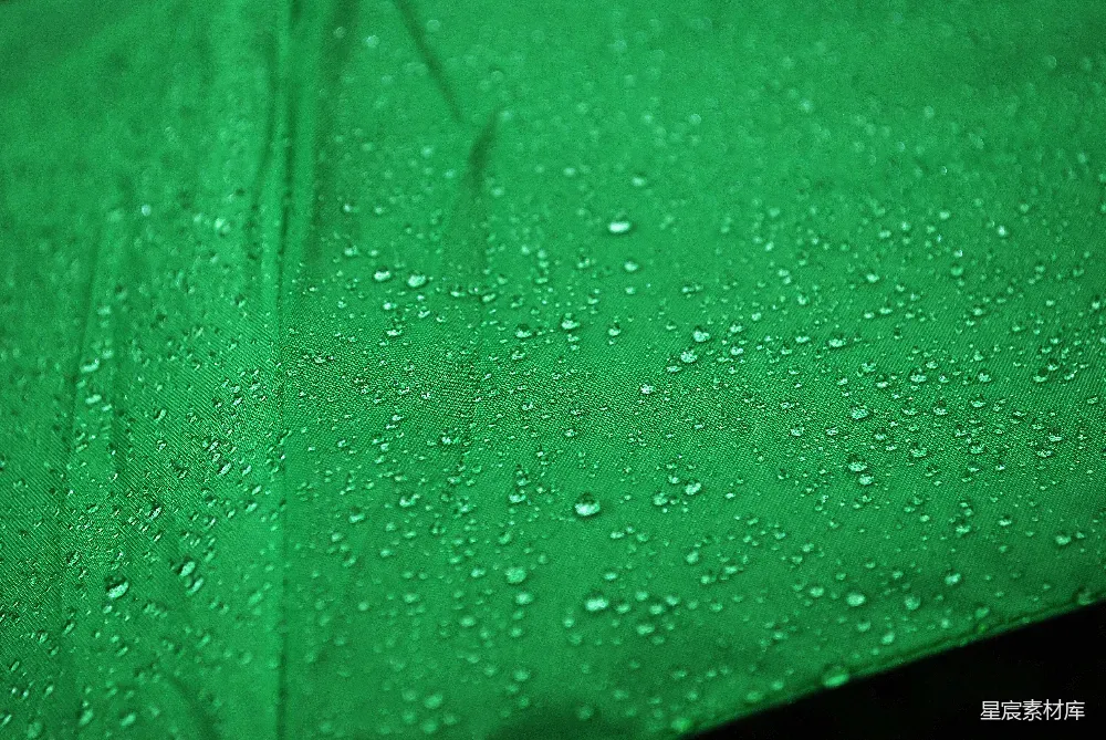 这张图片展示了雨后绿色植物上水滴的特写。水滴在光线下闪闪发光，呈现出一种清新自然的美感。图片以绿色为主调，给人一种宁静和放松的感觉。适合用作自然、环保或清新风格的背景图片。