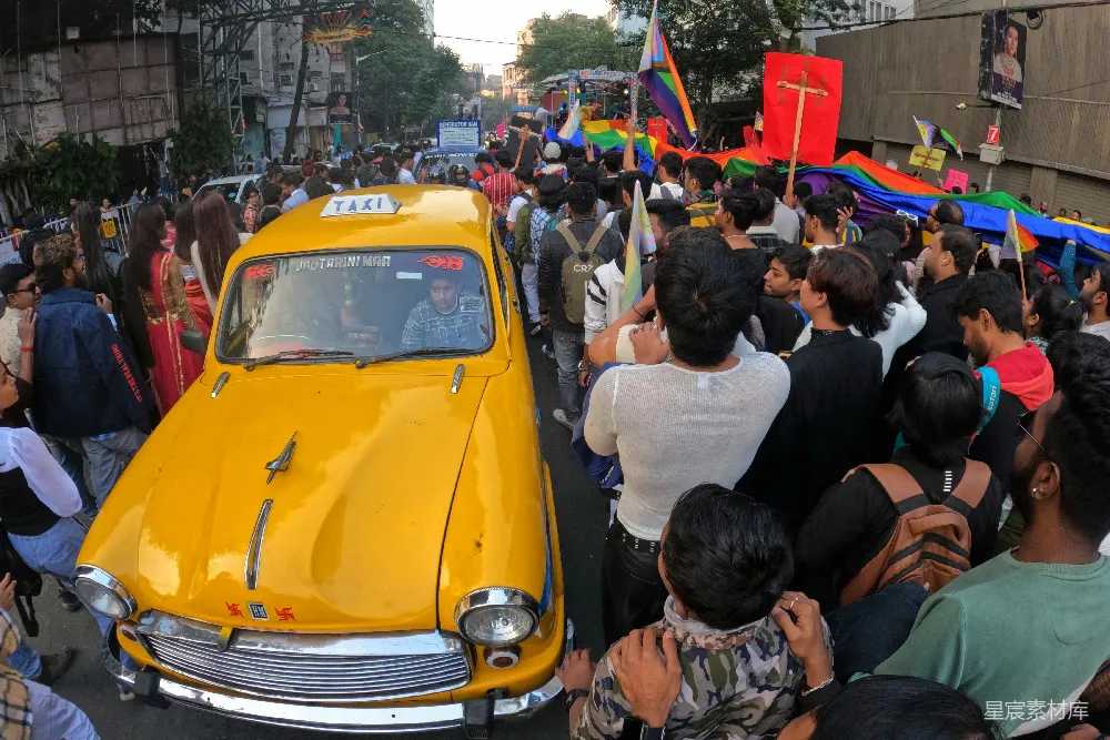 高清摄影 印度 LGBTQ+ 游行 黄色出租车 街头艺术 一群人在一辆黄色的出租车周围站立着。