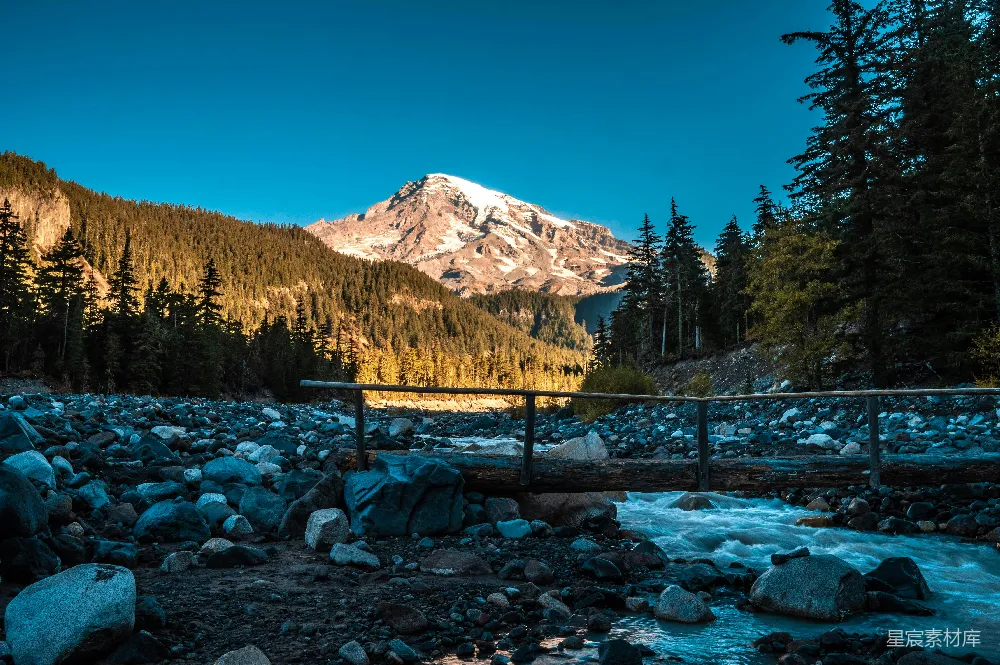 高清摄影  棕色木桥横跨覆有白雪的山上的河，在白天。