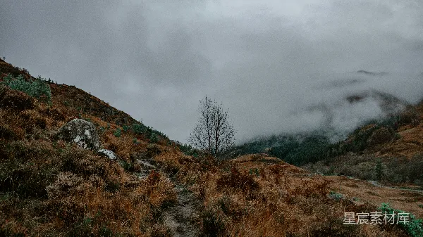 高清摄影 山坡上一条尘土路，在背景中有层云的天空中。