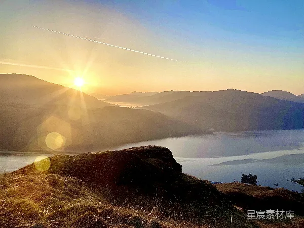 高清摄影 背景中有山丘和一片水面，夕阳在天边。