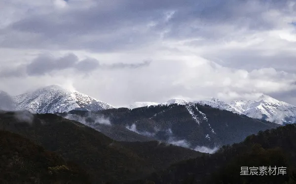高清摄影 白天云层覆盖下的山峦覆雪