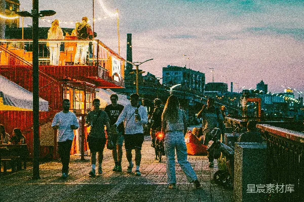 高清摄影 人们在傍晚沿着一条木板步行道行走。