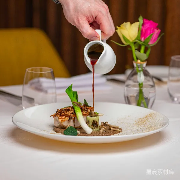 高清摄影 一个人将酱料倒在盘子中的食物上