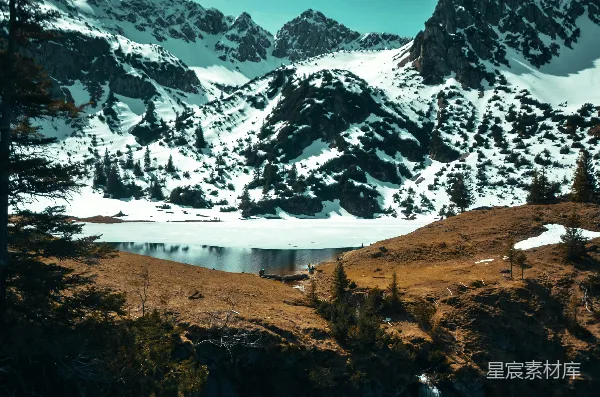 高清摄影 山脚下一片雪覆盖的山脉，湖水在前面。