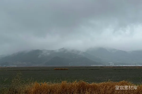 高清摄影 云雾山脉，阴沉的天空，一片枯黄的草地。