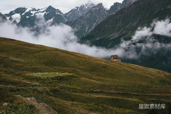 高清摄影 一座建在草坡上的房子，背景是山峦。