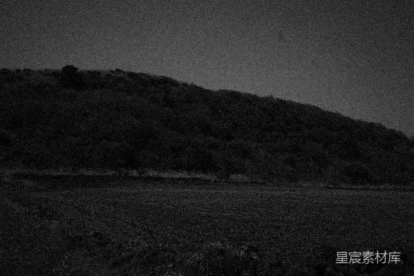 高清摄影 一片暗色的丘陵地带，前景有一片田野。
