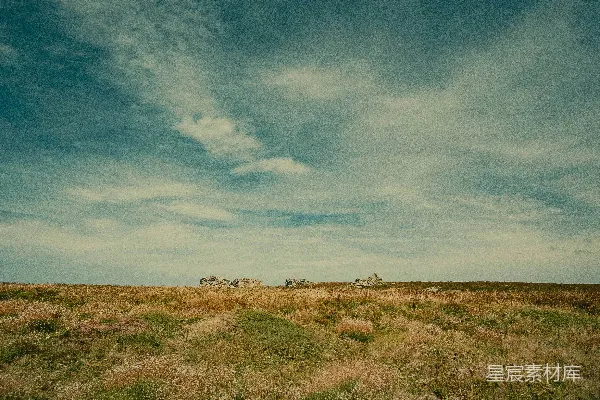高清摄影 远处有一片草地，几块石头在其中。
