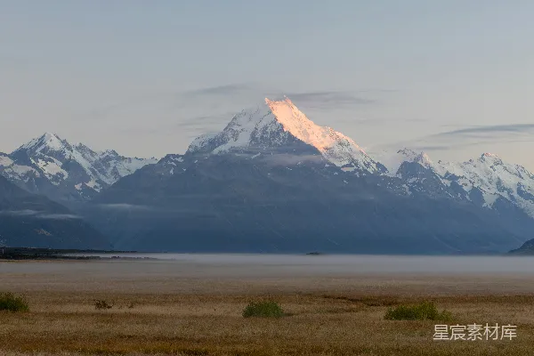 高清摄影 皑皑山峰在晨雾平原上沐浴着初升的太阳光辉。