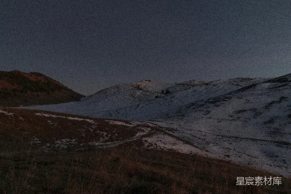 高清摄影 一片覆盖着白雪的山丘，在暗淡的夜空中显得格外明显。