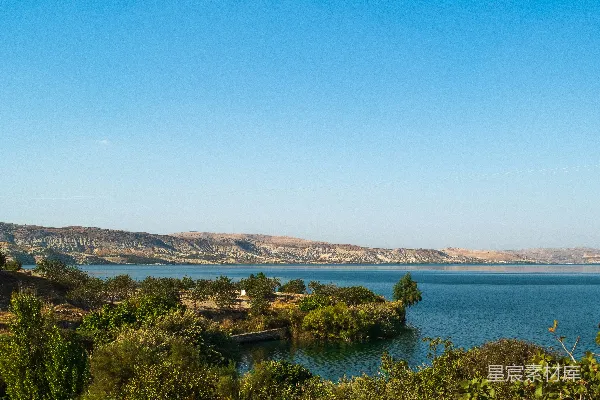 高清摄影 大片湖水周围绿树环绕，远处连绵的山峦。