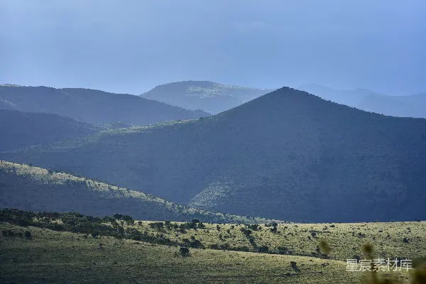 高清摄影 朦胧的蓝色山峦背景中有一片草地。
