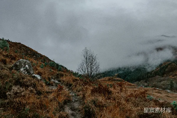 高清摄影 山坡上一条尘土路，在背景中有层云的天空中。