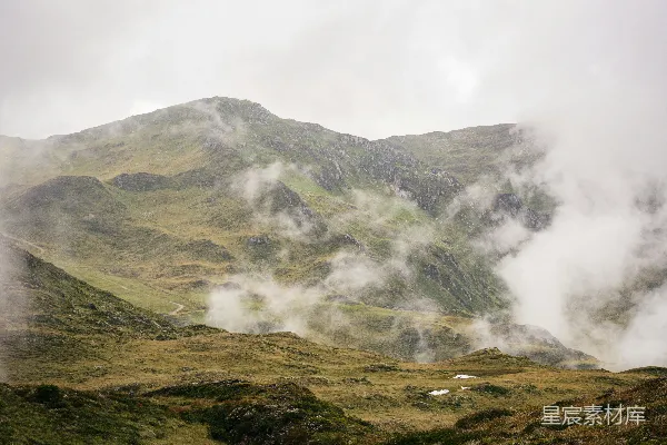 高清摄影 山脚下绿色草地旁白云间白天的景象