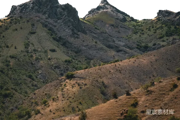 高清摄影 嶙峋的山峰高耸在起伏的干燥丘陵之上。