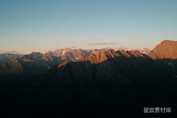 高清摄影 夕阳映照着山峰顶部的崎岖山峰，金光闪耀。