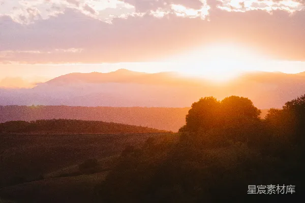 高清摄影 夕阳映照着起伏的山丘，远处有连绵的群山。