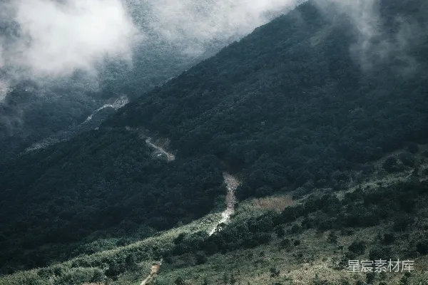 高清摄影 绿丘间蜿蜒的山路穿过雾气缭绕的山脉。