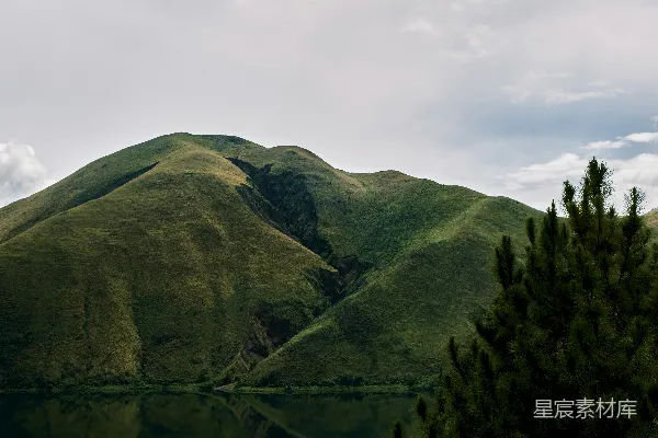 高清摄影 一座山峦前方有一片水域。