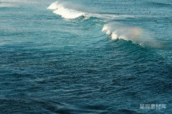 高清摄影 海边一个穿着冲浪板的人在波浪上骑行