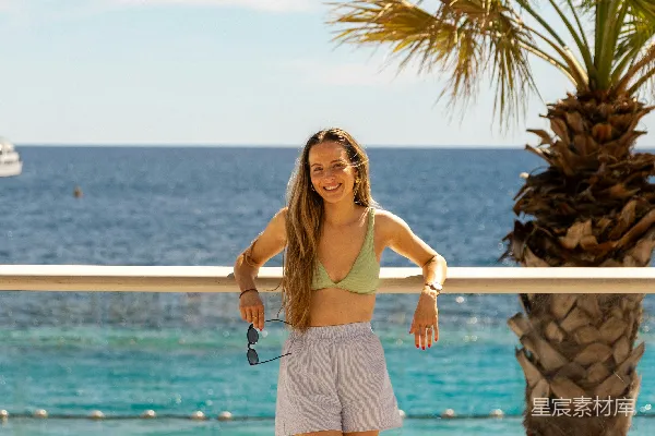 高清摄影 一位女性站在海边棕榈树旁的位置上。