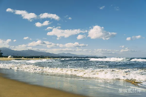 高清摄影 一片沙滩，海浪涌向岸边。