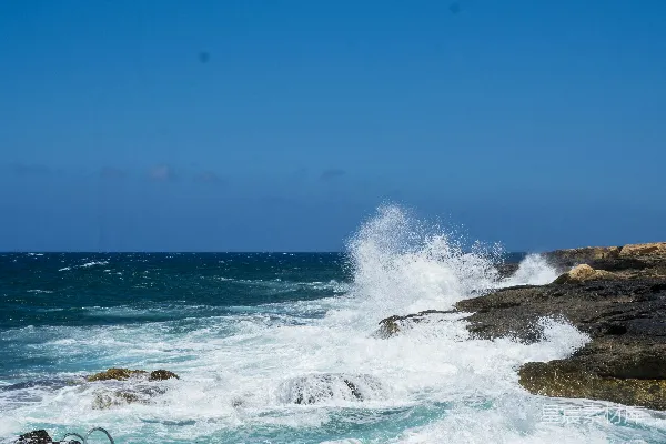 高清摄影 一块石头上坐着的长凳位于靠近海洋的一片岩石海滩旁。