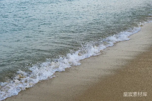 高清摄影 一片沙子覆盖的海滩，海浪涌向岸边