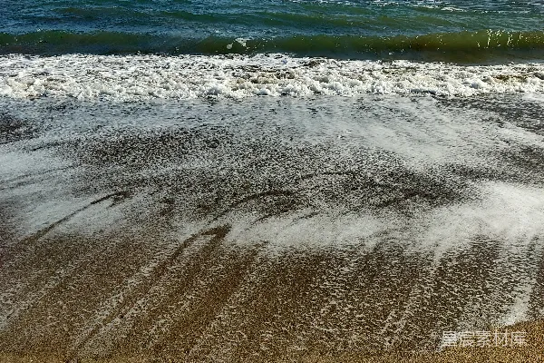 高清摄影 一片沙子覆盖的海滩，海水时而涌进，时而出现。