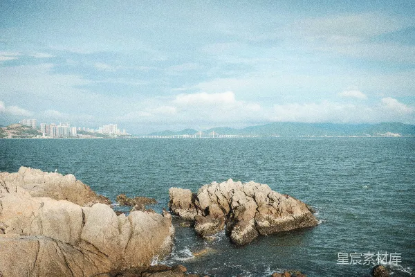 高清摄影 前景有岩石，背景是城市的水面