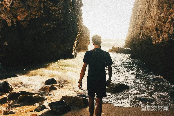 高清摄影 一个人站在海边沙滩上，靠近海边岩石。