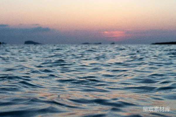 高清摄影 在日落时分平息海浪，远处岛屿隐约可见