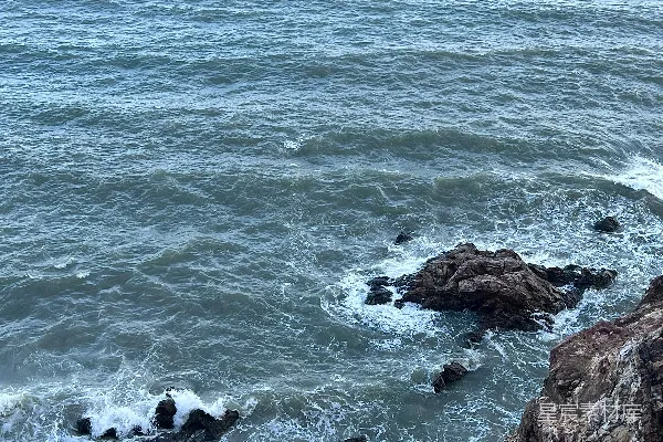 高清摄影 一个男人坐在岩石上，旁边是海洋。