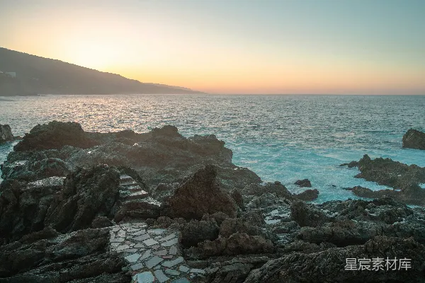 高清摄影 夕阳西下，映照着海边的岩石。