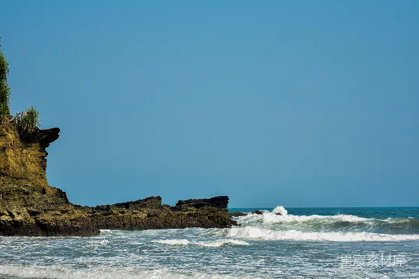 高清摄影 海滩上一块岩石露出物，海浪在其前方拍打。