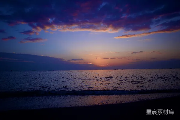 高清摄影 海滩上的水边正落下夕阳。