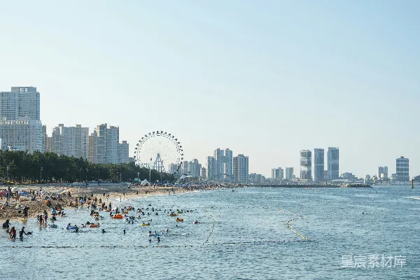 高清摄影 海滩上人声鼎沸，背景中有摩天轮。
