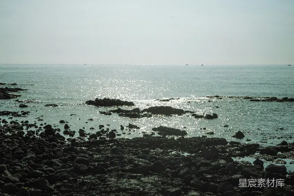 高清摄影 岩石海岸与平静闪耀的海洋水相遇。
