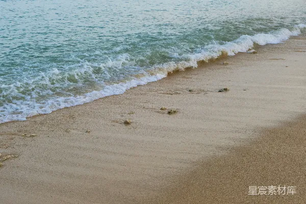 高清摄影 一片沙白的海滩，海浪涌向岸边。