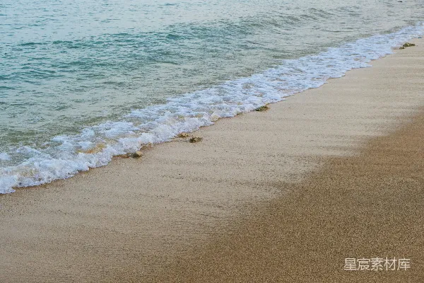 高清摄影 一片沙子铺就的海滩，海浪涌向岸边。