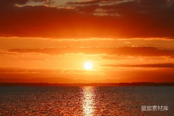 高清摄影 背景中有一处广阔的水域，夕阳西下。