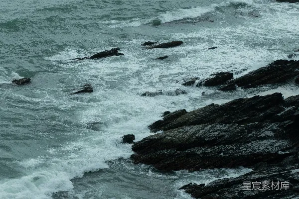 高清摄影 一块岩石嶙峋的海滩，海浪拍击著它。
