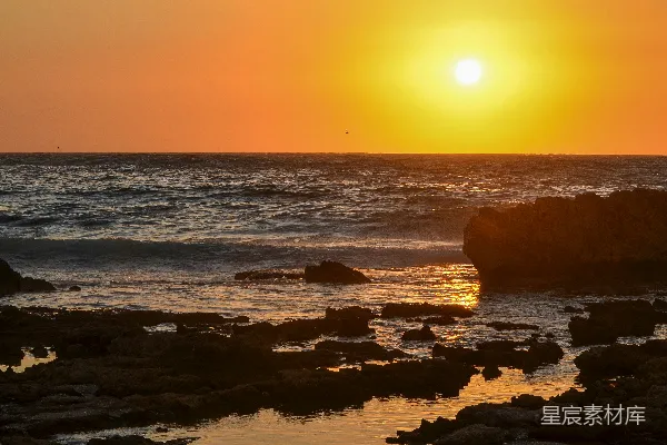 高清摄影 夕阳西下，海平面上有岩石在前景。
