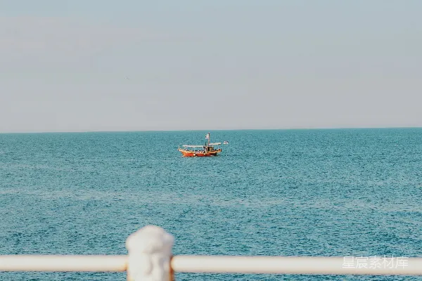 高清摄影 远处有一叶扁舟，蓝色的海面上有白色的栏杆。