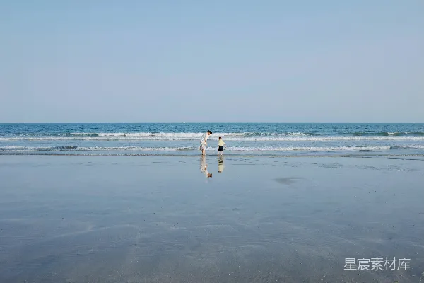 高清摄影 人们站在海滩上，旁边是倒影。